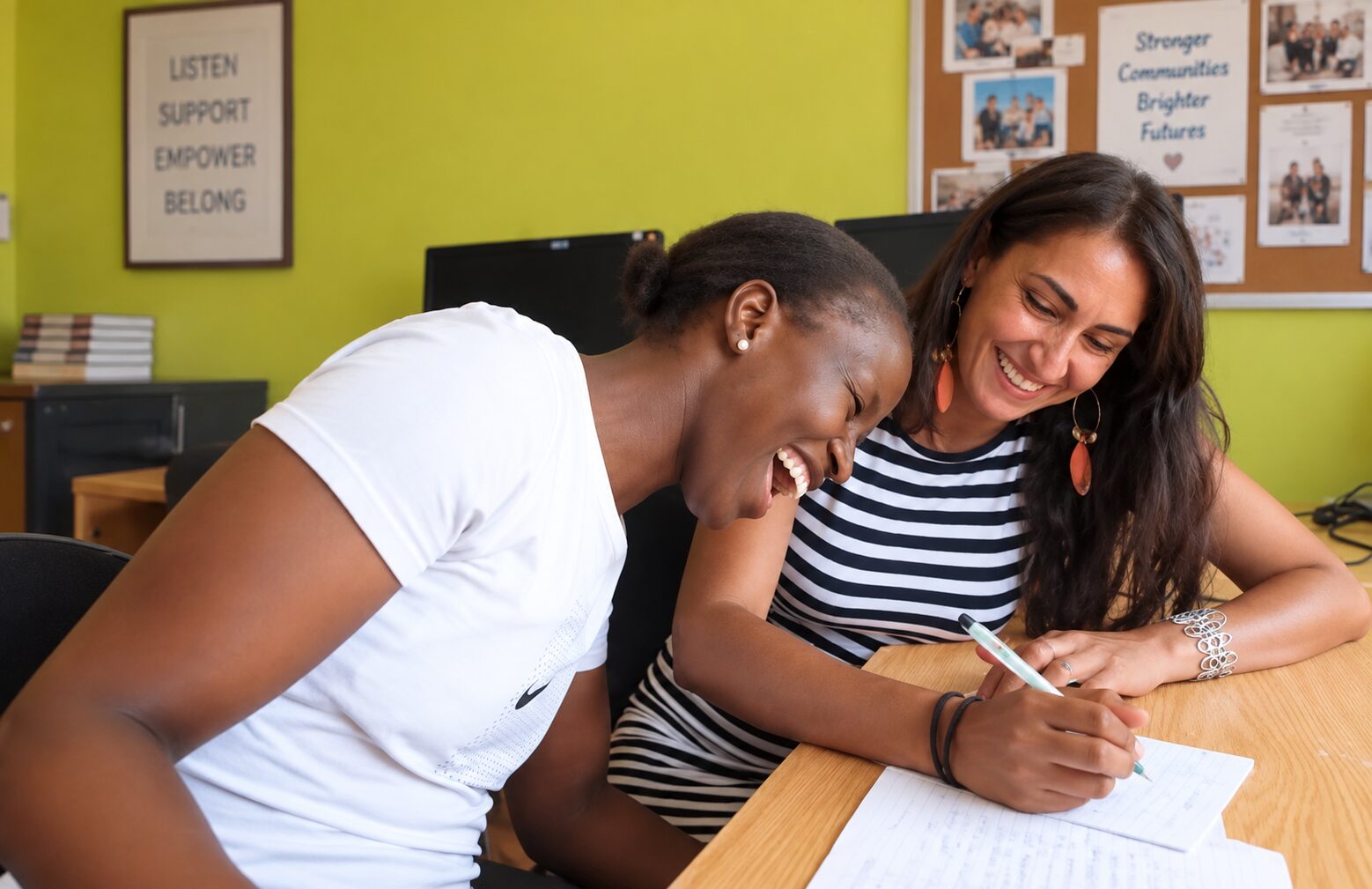 Two women laughing together while reviewing notes during a human rights internship activity in Cape Town.