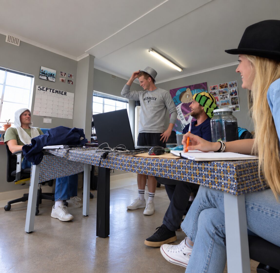 Small creative team discussing ideas around a table in an informal office workspace.