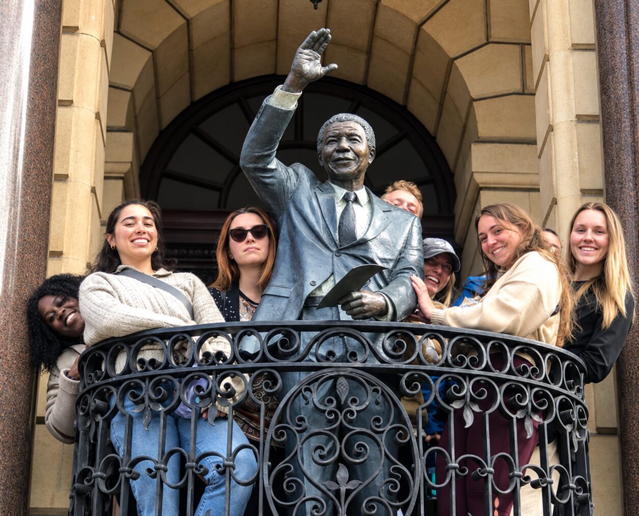Group of VAC participants gathered around a statue of Nelson Mandela on the balcony of Cape Town City Hall.