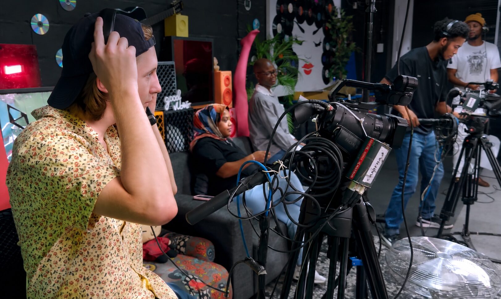 Behind-the-scenes film production setup with a cinema camera, monitor, lighting, sound equipment and clapperboard